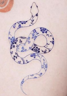 a blue and white snake tattoo on the back of a woman