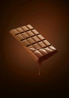 a chocolate bar with melted chocolate on it's side, in the middle of dark brown background