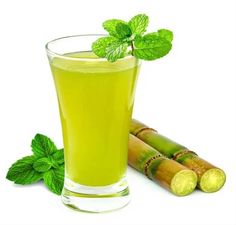 a tall glass filled with green liquid next to two rolled up bamboos and mint leaves