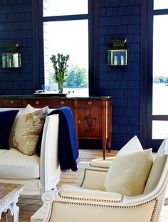 a living room filled with white furniture and blue brick wall behind the couch is a coffee table that has pillows on it