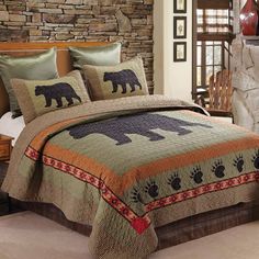 a bed with a bear and paw quilt on it's cover, in front of a stone wall