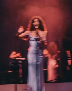 a woman in a blue dress standing on stage