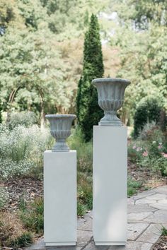 two white vases sitting on top of cement blocks