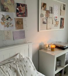 a white bed sitting next to a window with pictures on the wall and candles in front of it