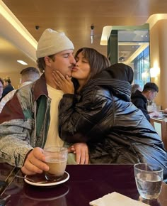 a man and woman kissing while sitting at a table