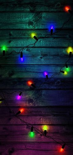 colorful lights are hanging on a wooden wall in the dark, and there is no image here to provide a caption for