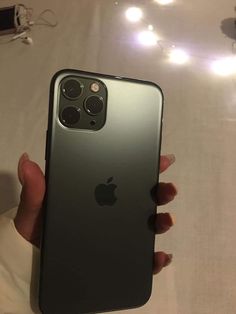 a person holding an iphone 11 in their left hand, with the back camera open