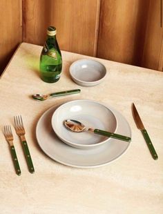 the table is set with silverware and green cutlery, along with a bottle of wine