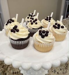 cupcakes with white frosting and chocolate toppings on a cake platter