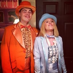 a man and woman dressed up in costumes posing for the camera with an orange suit on