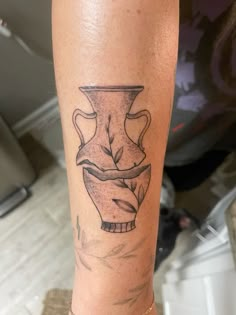 a woman's leg with a tattoo on it that has a vase in the middle