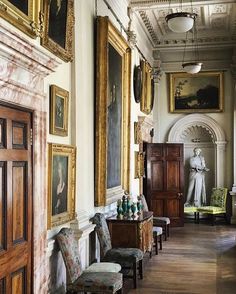 an ornate hallway with paintings on the wall and chairs in the foreground, along with other antique furniture