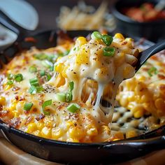 a spoon full of macaroni and cheese being lifted from a skillet