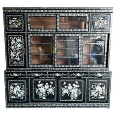 an ornate black and white china cabinet with flowers on the front, mirrored doors in the back