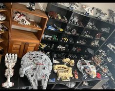 a collection of star wars toys and legos on display in a room full of shelves