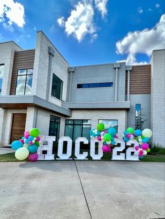 a large sign that says hooc2b in front of a building with balloons