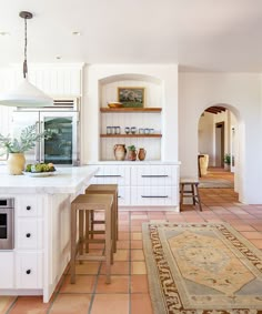 a large kitchen with white cabinets and an area rug on the floor in front of it