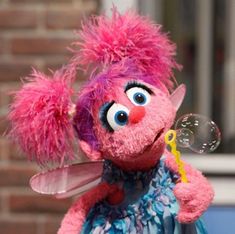 a pink stuffed animal with big eyes blowing bubbles