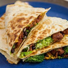 two burritos on a blue plate with broccoli