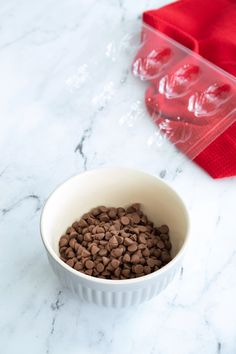 a white bowl filled with chocolate chips on top of a counter next to a red napkin