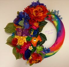 a rainbow colored wreath with flowers and leaves