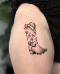 a woman's thigh with a tattoo of a boot and flowers on the side