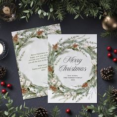 two christmas cards with pine cones and greenery on the side, surrounded by evergreen branches