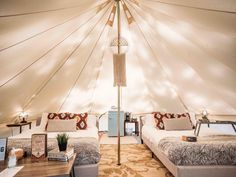 two beds in a large tent with lights on the ceiling and pillows on the floor