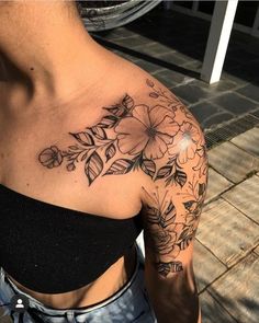 a woman with a flower tattoo on her shoulder and chest is looking at the camera