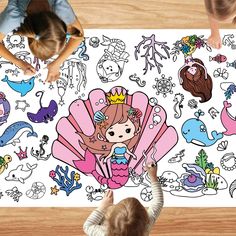 two children are looking at a drawing on the floor with mermaids and sea creatures