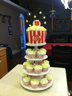 a three tiered cake with cupcakes on the bottom and popcorn in the middle