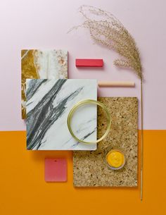 an assortment of items on a table including a candle, marble coaster and gold ring