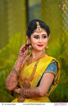 a woman in yellow and blue sari with henna on her head, posing for the