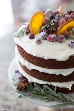 a frosted cake with orange slices and berries on top