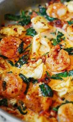 a pan filled with shrimp and spinach covered in sauce