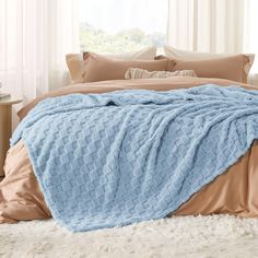 a bed covered in a blue blanket and pillows