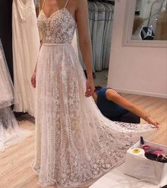 a woman standing in front of a dress on display at a bridal shop while another person lays on the floor next to her