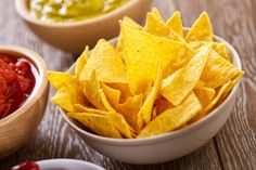 three bowls filled with chips and salsa on top of a wooden table