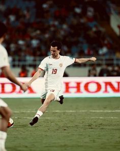 a man kicking a soccer ball on top of a field