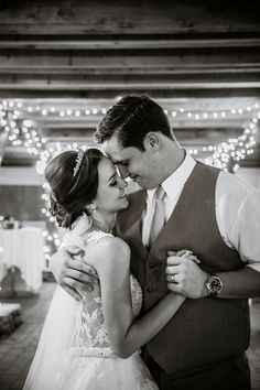 a bride and groom kissing in front of christmas lights at their wedding reception, black and white photo