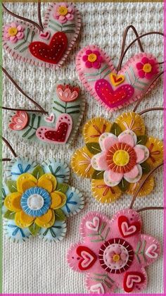 several colorful flowers and hearts are hanging from a wire on a tablecloth with a pink frame