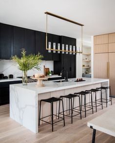 a kitchen with black cabinets, white countertops and bar stools next to an island