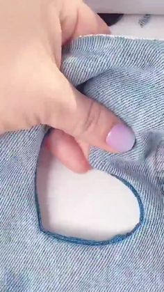 a woman's hand holding onto a blue and white shirt with a heart shaped patch