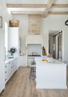 a large kitchen with white cabinets and wood beams on the ceiling is pictured in this image