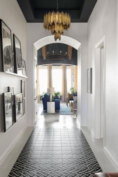 a hallway with black and white tile flooring and chandelier hanging from the ceiling