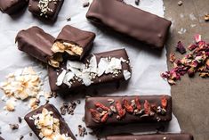 chocolate bars with nuts, coconut and other toppings laid out on a piece of parchment paper