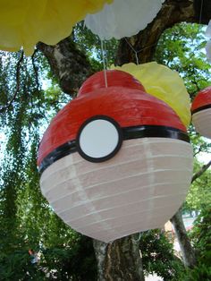 paper lanterns in the shape of pokeballs hanging from a tree