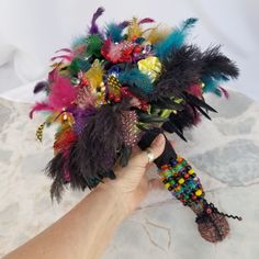 a person holding a bouquet with feathers and beads in their hand on a marble surface