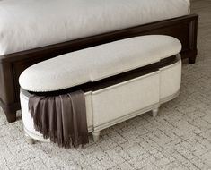 a bed with a white blanket on top of it next to a footstool