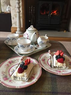 three plates with desserts on them sitting in front of a fireplace